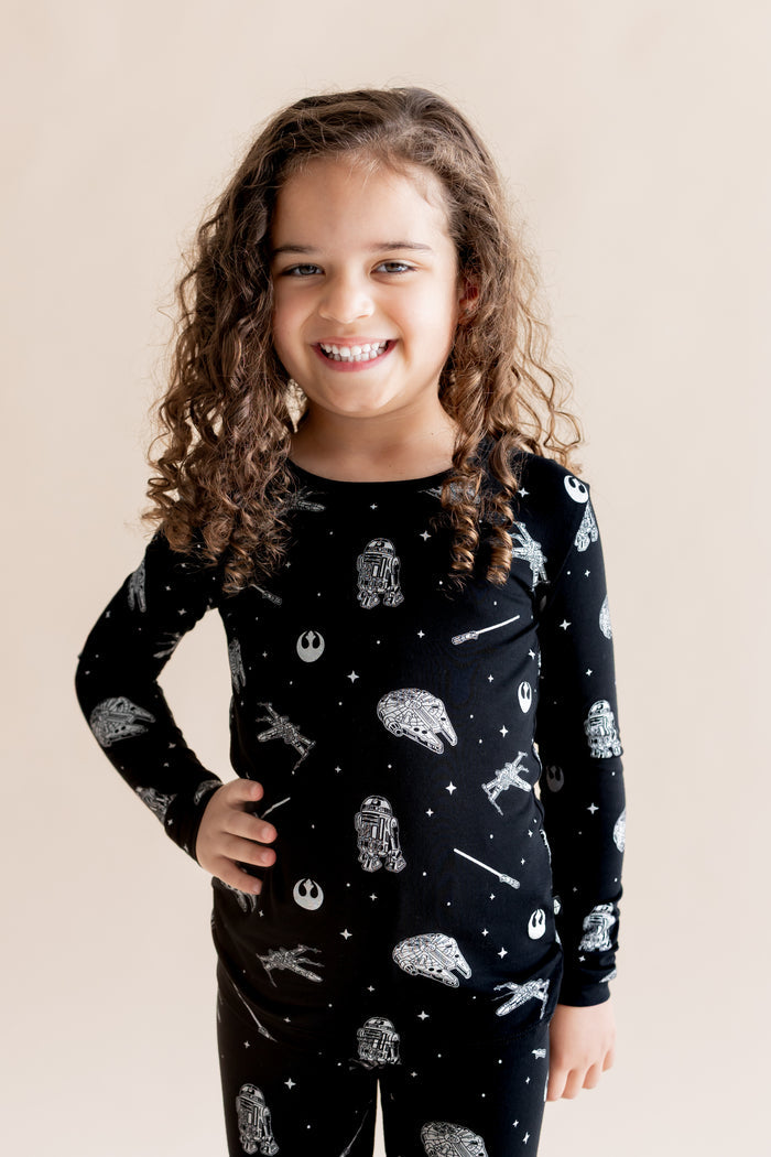 Girl smiling in Long Sleeve Pajamas in STAR WARS™ print on a cream background