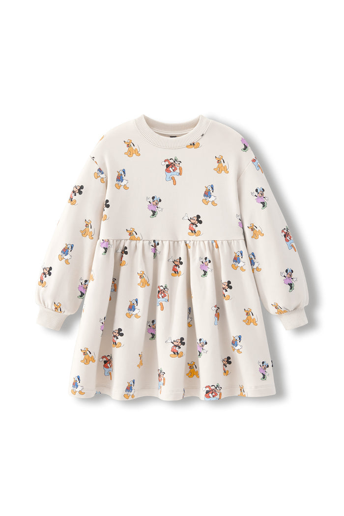 A long-sleeve baby dress in cream with a colorful cartoon mickey character print, featuring a gathered waist and elastic neckline, shown against a plain white background.