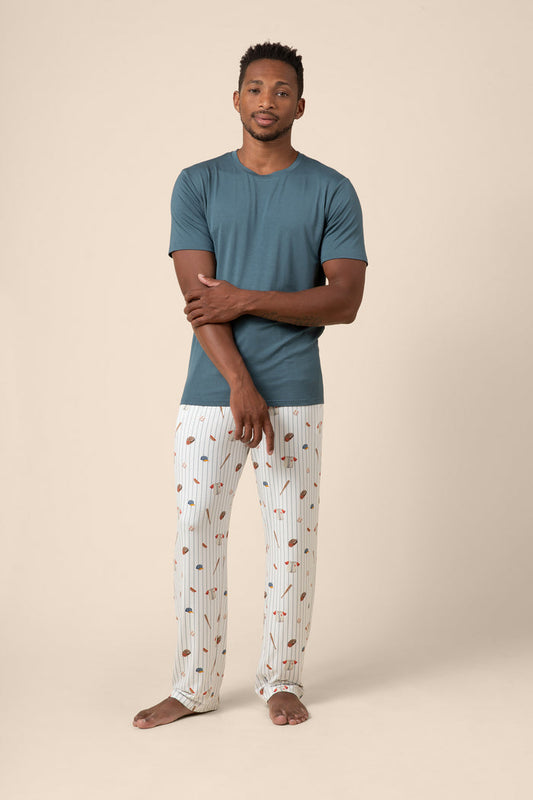 Man wearing a blue t-shirt and baseball patterned pants on a beige background