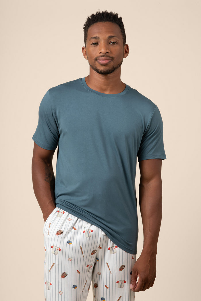 Man wearing a blue t-shirt and baseball patterned pants on a beige background
