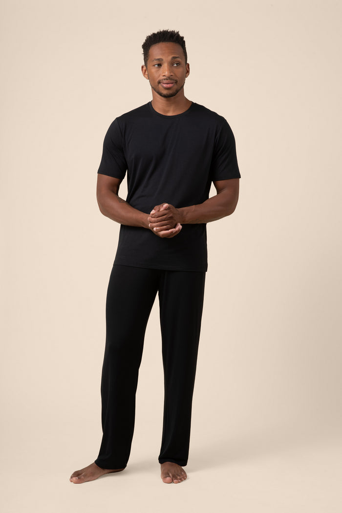 Man wearing a black t-shirt and black pants on a beige background