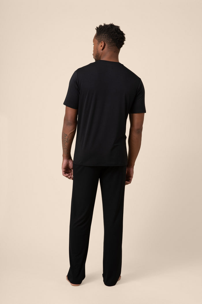Man wearing a black t-shirt and pants on a beige background