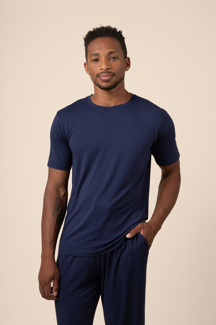 Man wearing a navy blue t-shirt and pants on a beige background