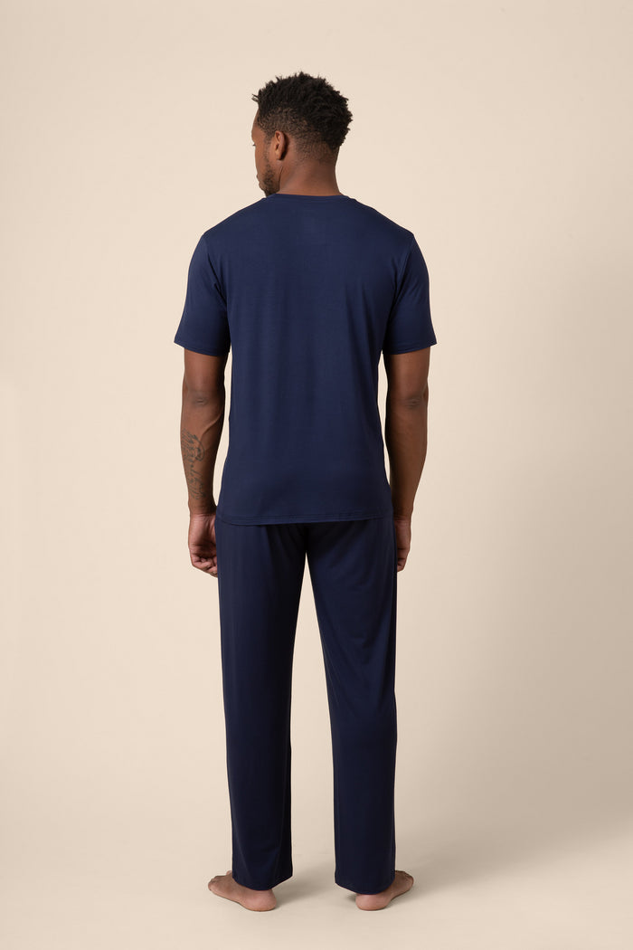 Man wearing navy blue pajama set on a beige background