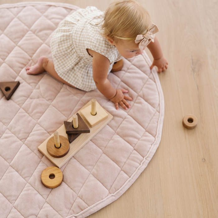 Baby girl crawling on a pink minky play mat.
