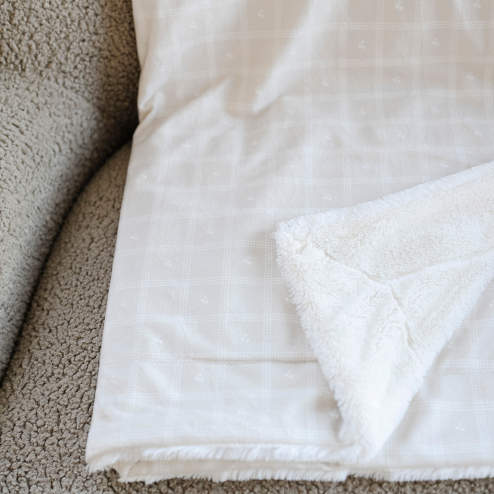 An up-close photo of a luxuriously soft Saranoni minky/lush blanket. This premium dual-textured extra-large throw features Saranoni’s signature cream lush fabric on one side and ultra-soft square printed minky on the other. Designed for ultimate relaxation, this plush blanket is perfect for snuggling, movie nights, and adding a touch of luxury to any home. This soft blanket is a luxury blanket and a Saranoni blanket. The cozy blanket is a perfect comfort item and a comfortable blanket.
