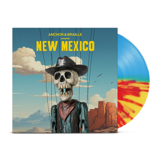 A half blue/half yellow/half orange splatter vinyl peeks out of a mainly blue jacket with an image of the desert with a blue sky with clouds. In front of the background is a skeleton dressed as a western cowboy with strings holding him up. The yellow text on the jacket reads "Anchor&Braille presents New Mexico".