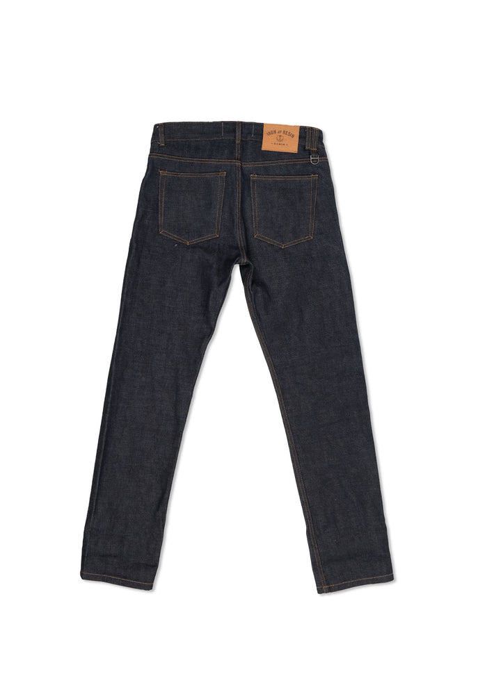 Back view of dark blue denim jeans with visible stitching and a brown leather patch on the waistband, isolated on white.
