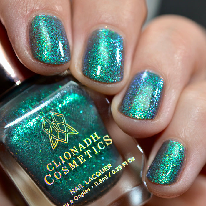 Close-up of nails painted with Nucleus Accumbens Nail Lacquer on fair skin tone. Hand is holding polish bottle.