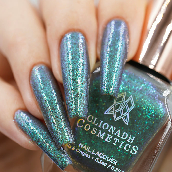 Close-up of nails painted with Nucleus Accumbens Nail Lacquer on fair skin tone. Hand is holding polish bottle.