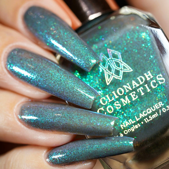 Close-up of nails painted with Nucleus Accumbens Nail Lacquer on fair skin tone. Hand is holding polish bottle.