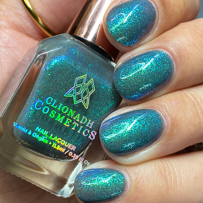 Close-up of nails painted with Nucleus Accumbens Nail Lacquer on fair skin tone. Hand is holding polish bottle.