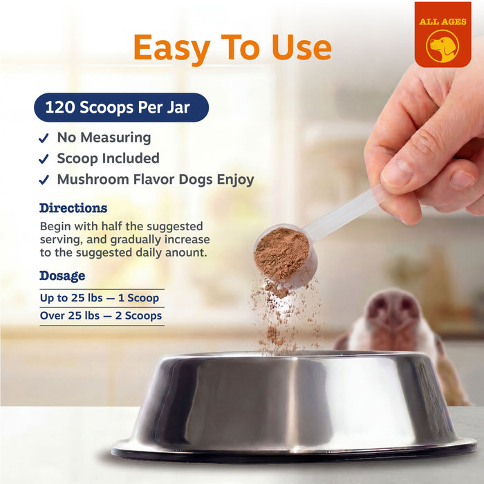 Hand holding scoop dispensing brown mushroom powder into stainless steel dog bowl.