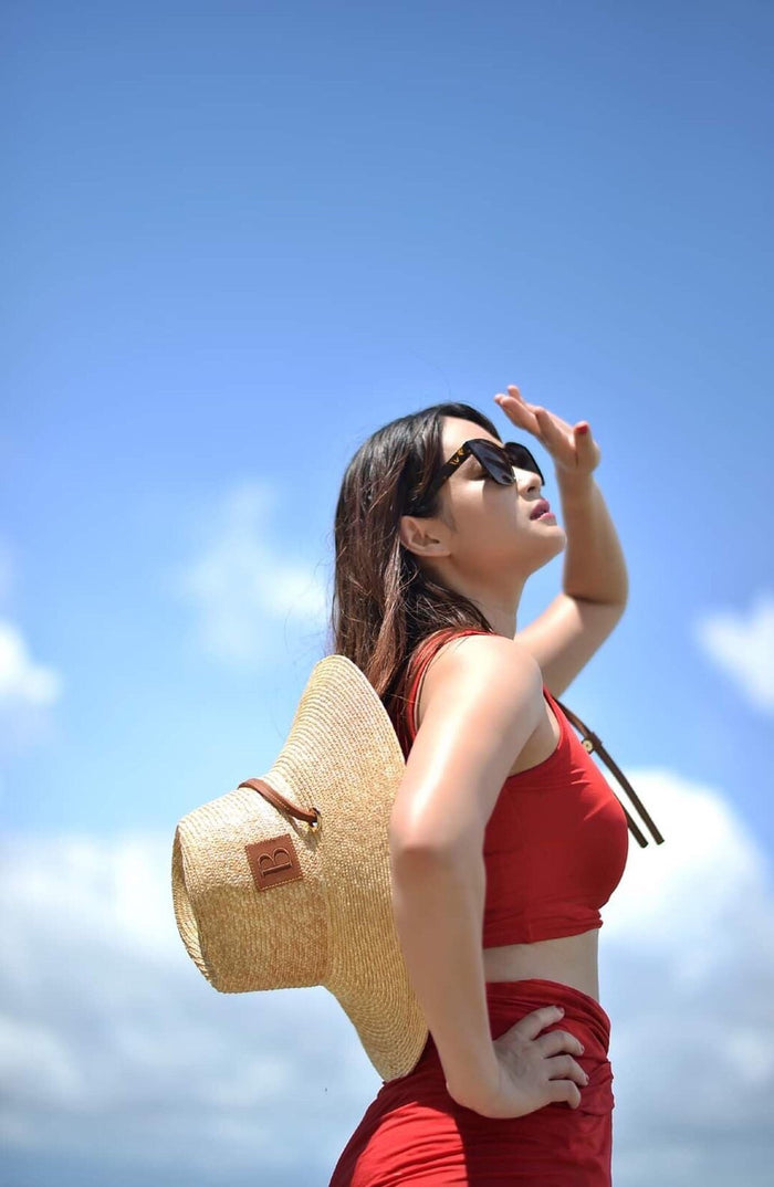 Woman wearing a panama wheat hat from Travellers Hat Boutique with sunglasses under blue sky