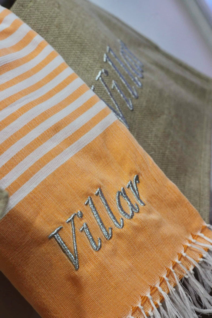 Personalized beach towel with Villar embroidery in orange and beige striped design with fringed edges