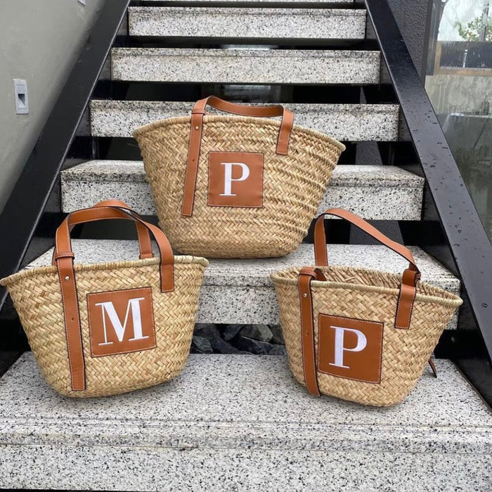 Set of three seagrass basket handbags with brown leather straps and initial patches by Travellers Hat Boutique