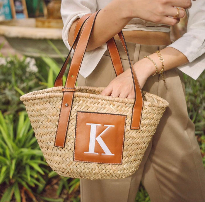 Traveller Hat Boutique seagrass basket handbag with leather straps and monogram patch being carried