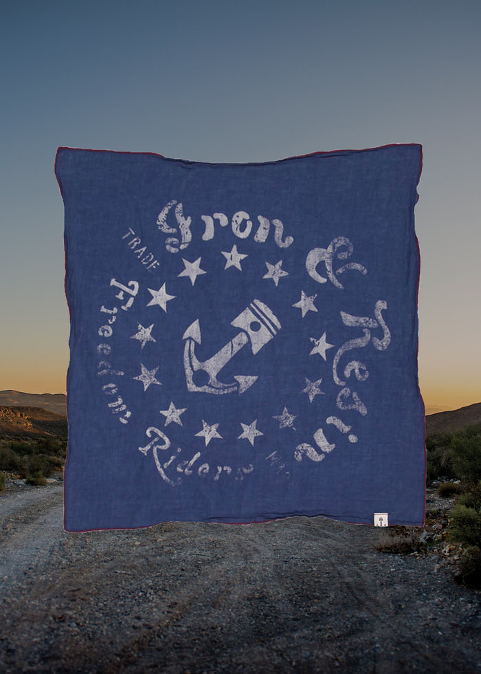 Blue bandana with anchor and stars design, labeled "Iron & Resin," hangs against a desert landscape at dusk.