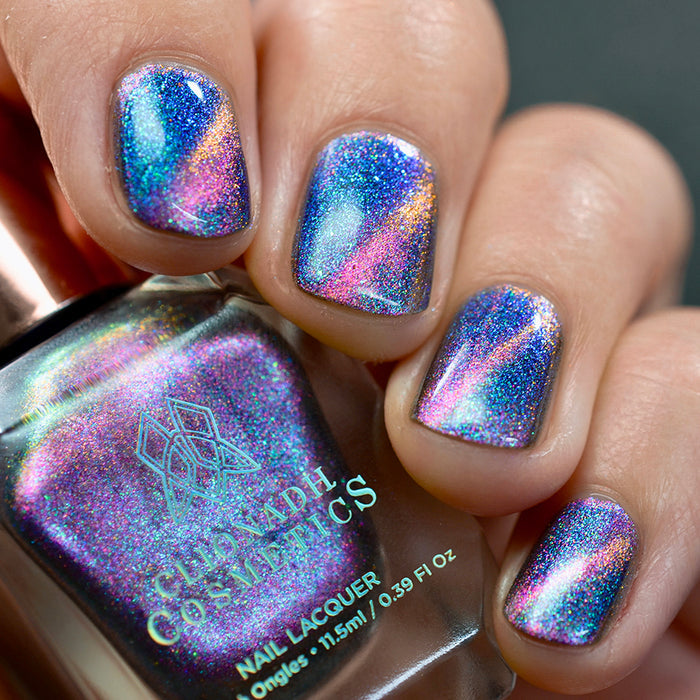 Close-up of nails painted with Psilocin Nail Lacquer on fair skin tone. Hand is holding polish bottle.