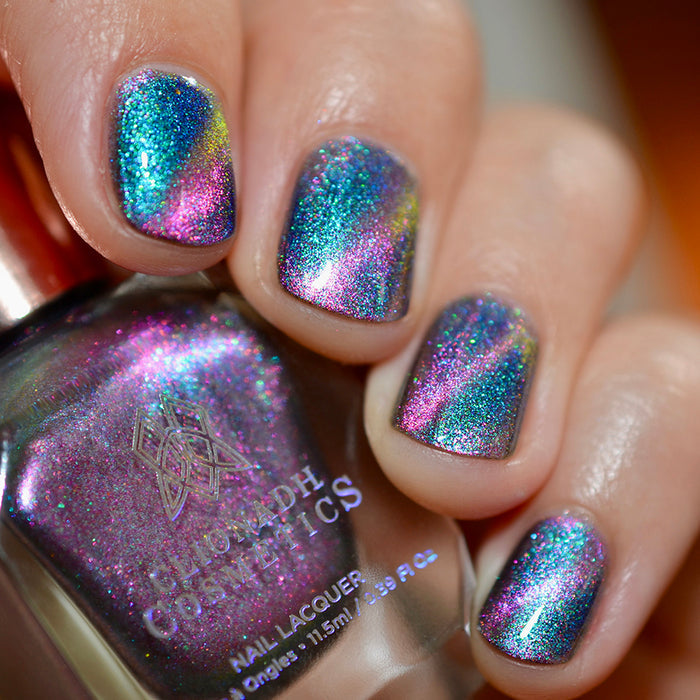 Close-up of nails painted with Psilocin Nail Lacquer on fair skin tone. Hand is holding polish bottle.