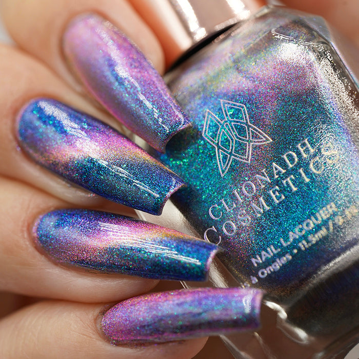 Close-up of nails painted with Psilocin Nail Lacquer on fair skin tone. Hand is holding polish bottle.
