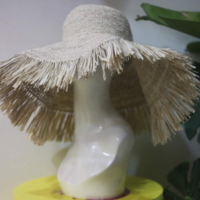 Beige raffia crochet sun hat with wide brim and fringed edges displayed on a mannequin head