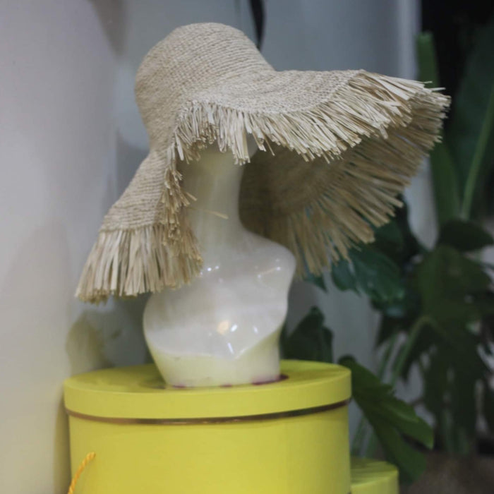 Beige raffia crochet sun hat with wide fringed brim on mannequin head at Travellers Hat Boutique