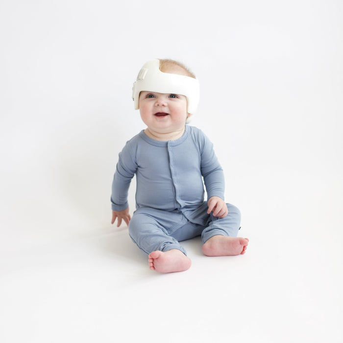 Baby sitting in white room wearing a Kyte Baby Romper  in Slate