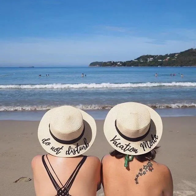 Two women wearing custom embroidered round hats with beach and ocean background at a sunny beach