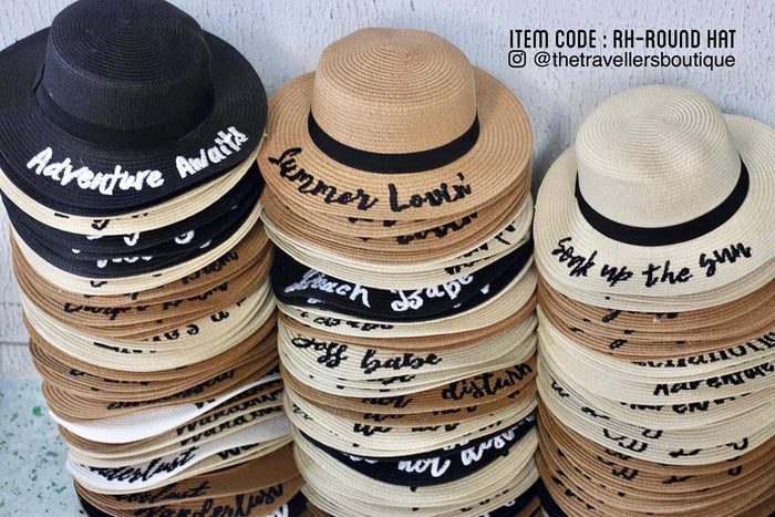 Stack of custom embroidered round hats in black, beige, and white colors with various text designs
