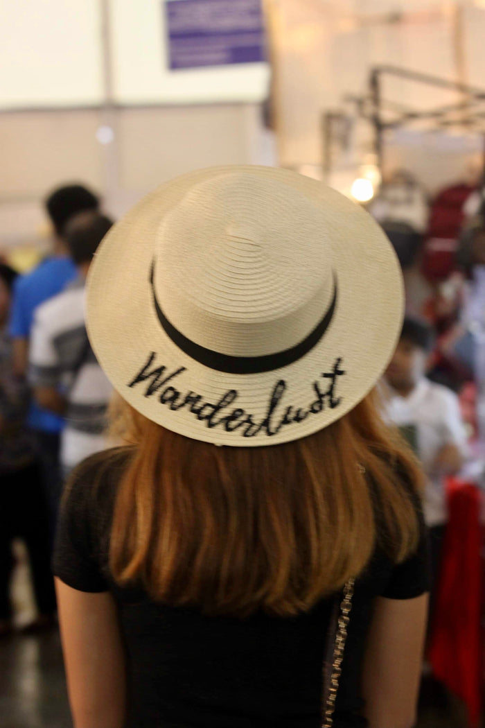 Custom embroidered round hat from Travellers Hat Boutique with Wanderlust design worn by woman