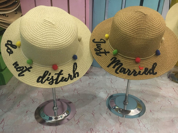 Custom embroidered round hat by Travellers Hat Boutique featuring colorful pom-poms and phrases do not disturb and just married