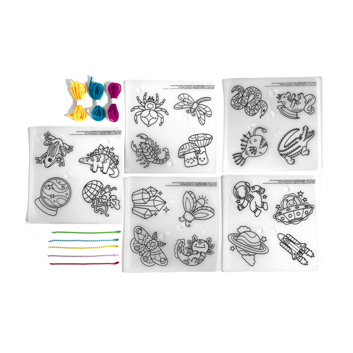 Contents of OOLY Glow Buddies Shrink-Its! DIY Shrink Art Kit including shrink pages, cords and beads.
