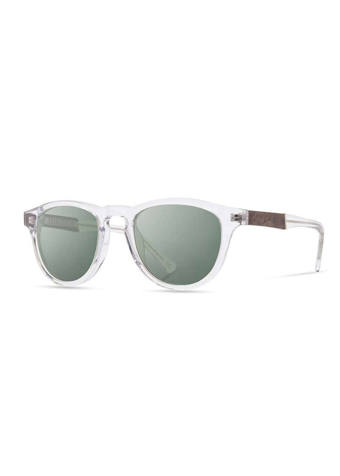 Clear-framed sunglasses with round green lenses and wooden temple accents, set against a white background.