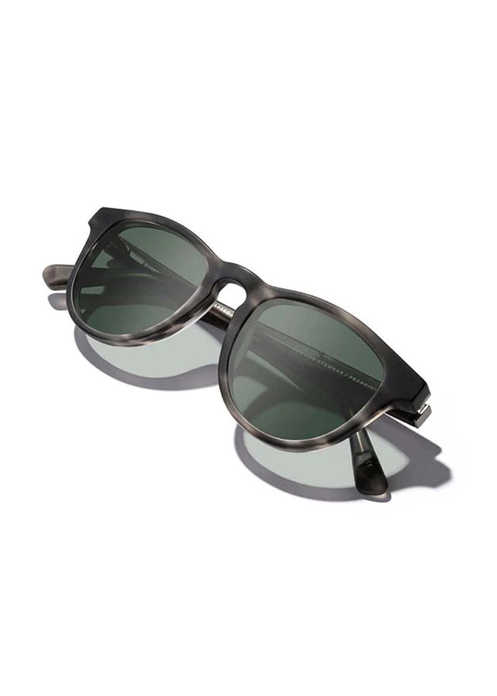 Stylish black sunglasses with round frames and dark lenses, casting a shadow on a white background.