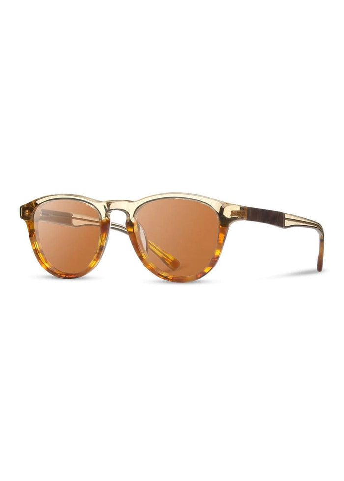 Stylish sunglasses with round amber lenses and tortoiseshell frames, set against a white background, showcasing modern design.