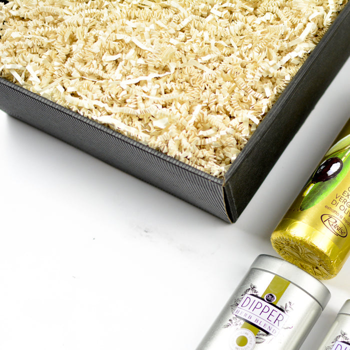 A matte black gift box with a ribbed texture is displayed open, filled with shredded paper.