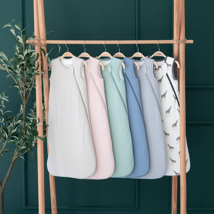 Different colors of Kyte Baby 2.5 TOG Sleep Bags hanging on wooden rack
