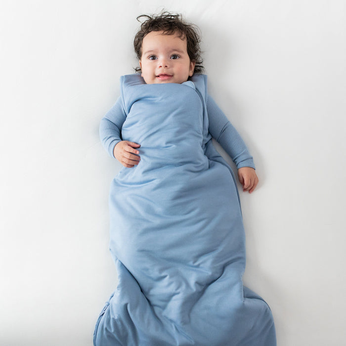 Baby wearing Kyte Baby Sleep Bag in Slate 2.5 with Ribbed Slate Bodysuit underneath