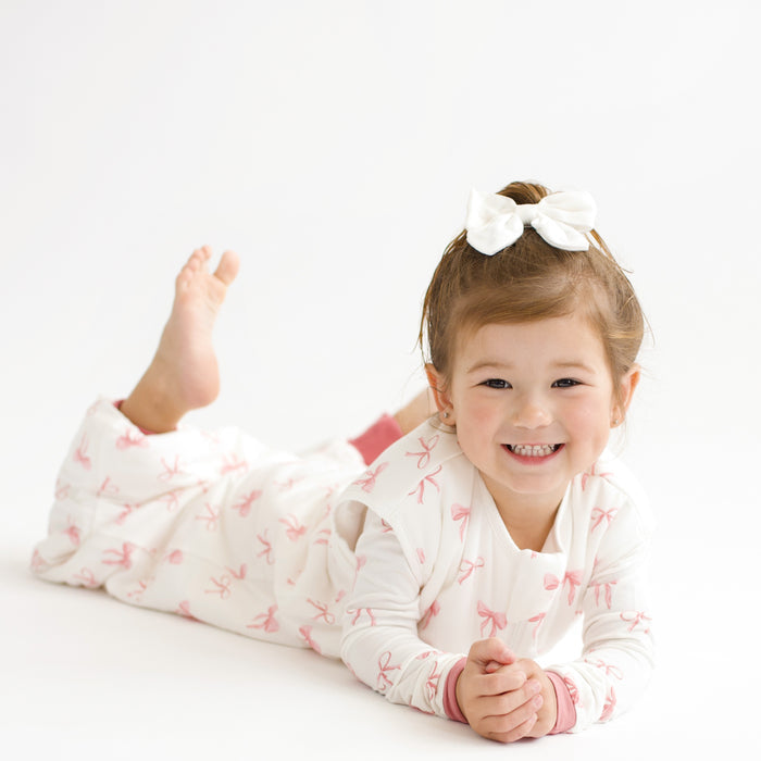 Toddler modeling Sleep Bag Walker in Bow 1.0 laying on stomach with feet up
