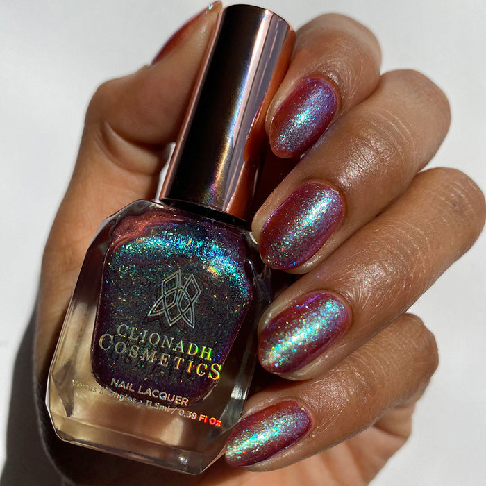 Close-up of nails painted with Smedge Haze Nail Lacquer on medium skin tone. Hand is holding polish bottle.