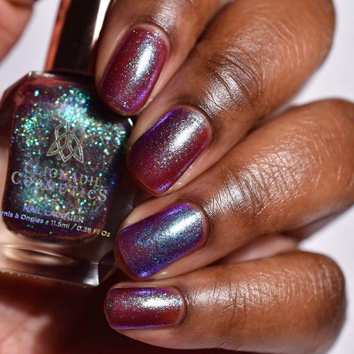 Close-up of nails painted with Smedge Haze Nail Lacquer on deep skin tone. Hand is holding polish bottle.