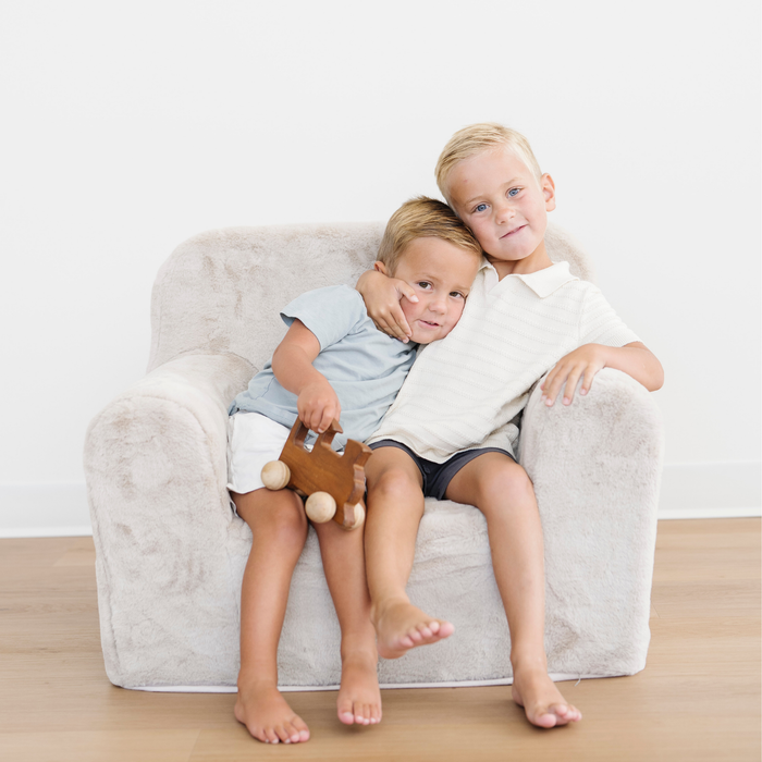 Brothers sit snuggled in a Saranoni faux fur snuggle up chair.