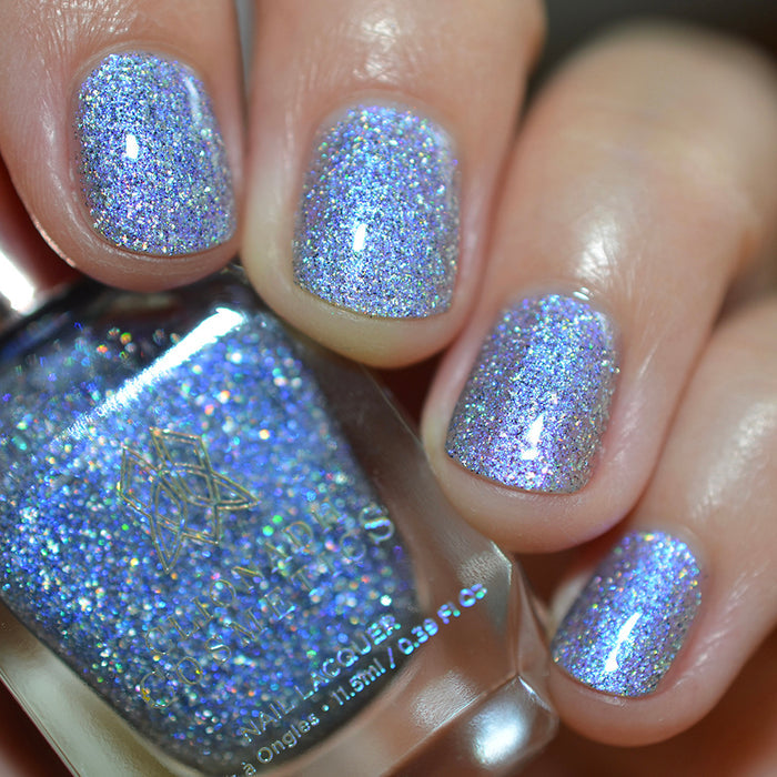 Close-up of nails painted with Spilled Salt Nail Lacquer on fair skin tone. Hand is holding polish bottle.