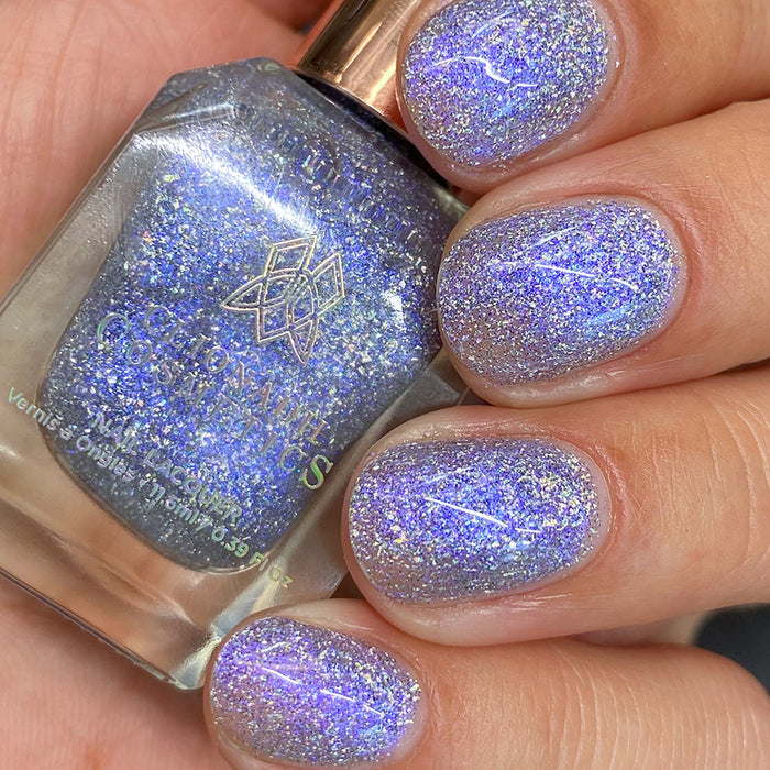 Close-up of nails painted with Spilled Salt Nail Lacquer on fair skin tone. Hand is holding polish bottle.