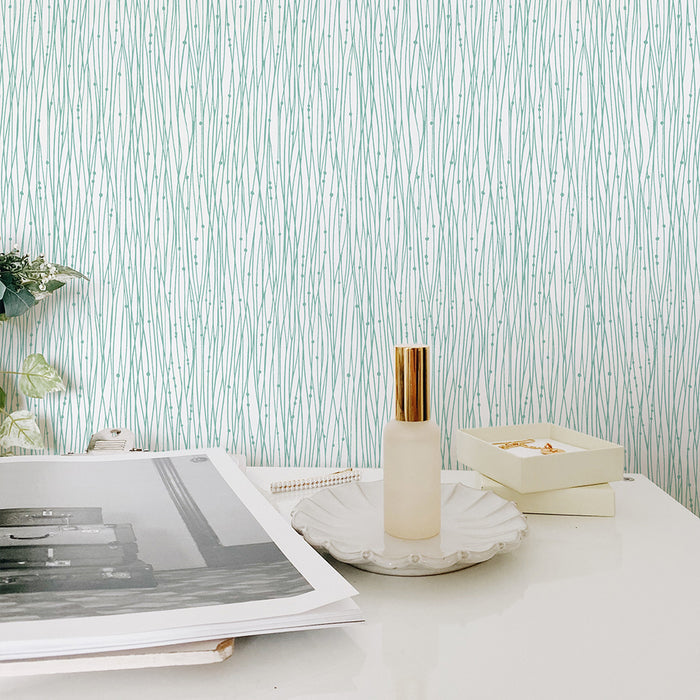 Tempaper's String of Pearls Peel And Stick Wallpaper in green behind a white table.