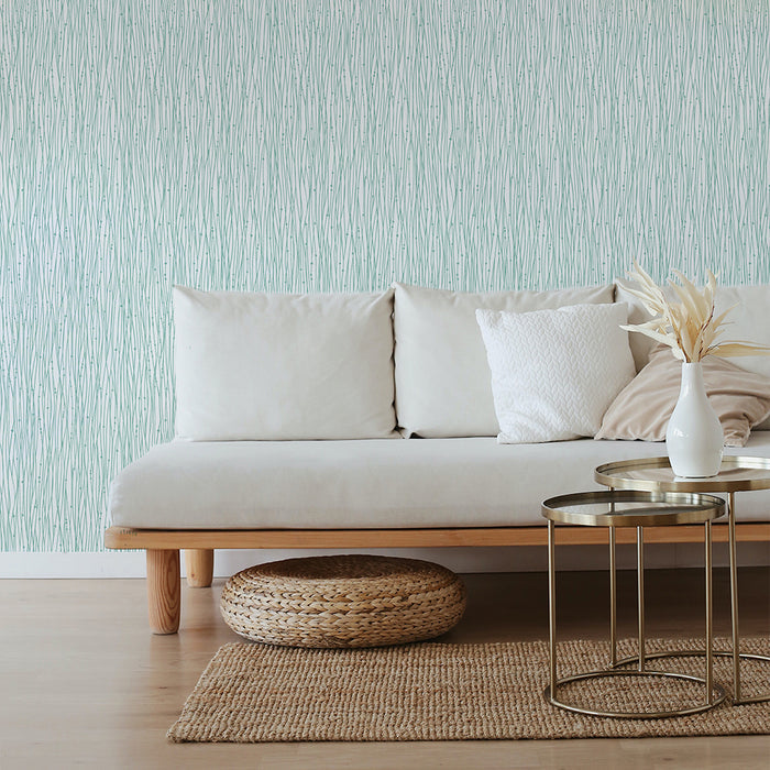 Tempaper's String of Pearls Peel And Stick Wallpaper in green behind a grey couch and bronze coffee table.