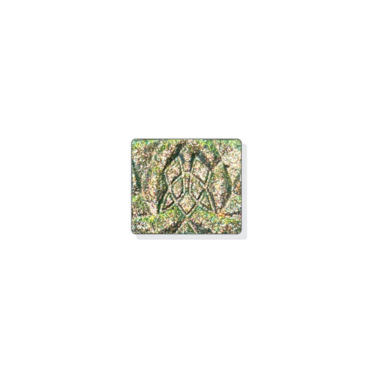 A single multichrome eyeshadow in colour Synthesis on a white background. A green-grey base and particles that shift copper-yellow-green with hints of silver and aqua sparkle.