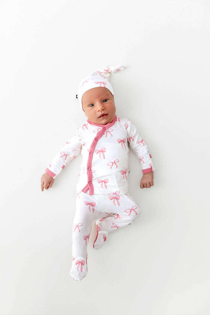 Baby in a white onesie with pink bows on a white background