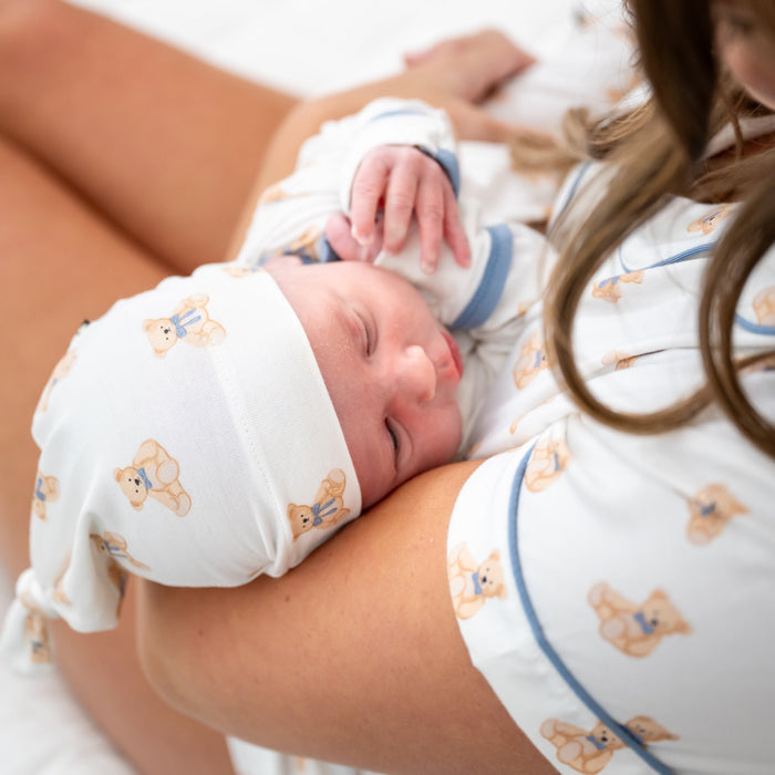 mom holding a newborn baby wearing a sweet teddy bear patterned pajama and cap